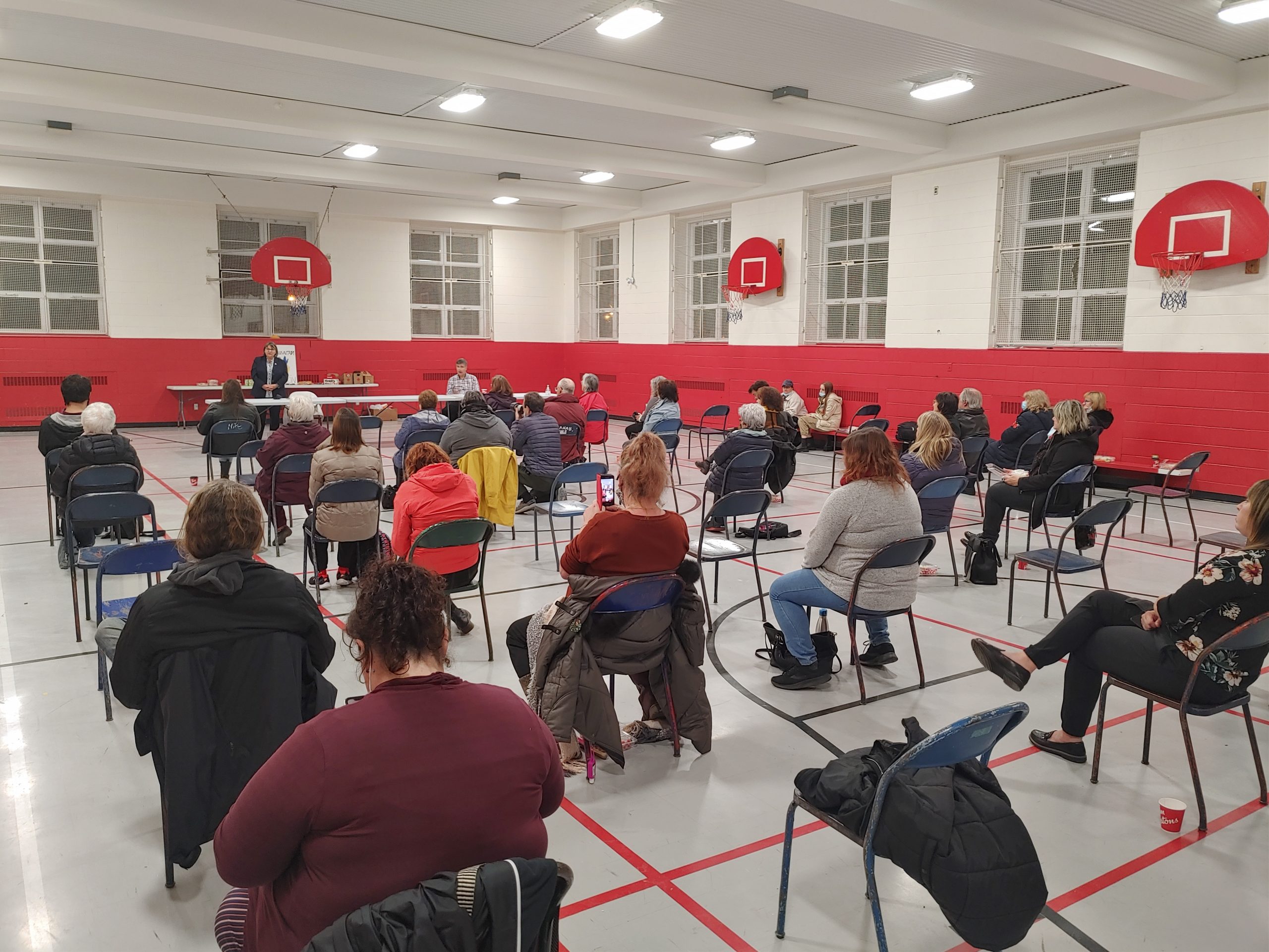 Soirée électorale municipale communautaire en mode élection 2021. Groupe de personnes assis sur des chaises dans un gymnase regardant candidat·e